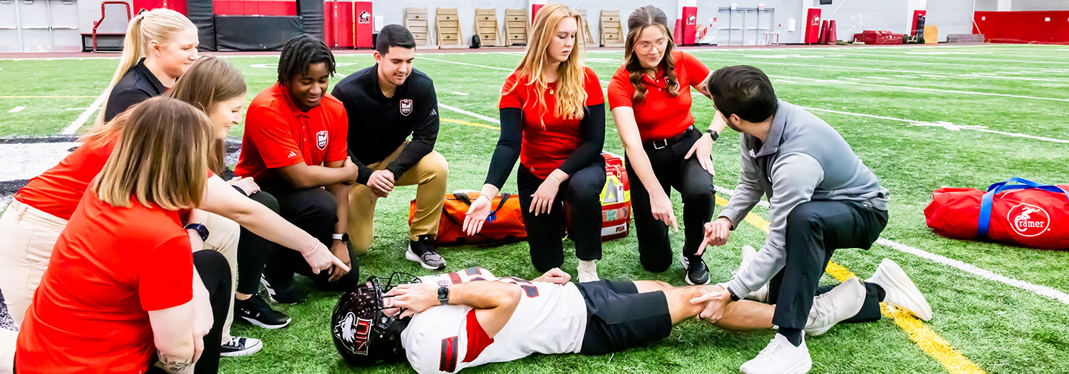 Group of Rehabilitation students on in practice facility with football player undergoing assessment