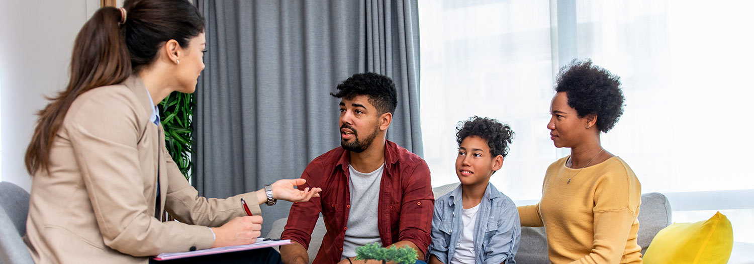 Family of three in an office interacting with a professional holding a clipboard 