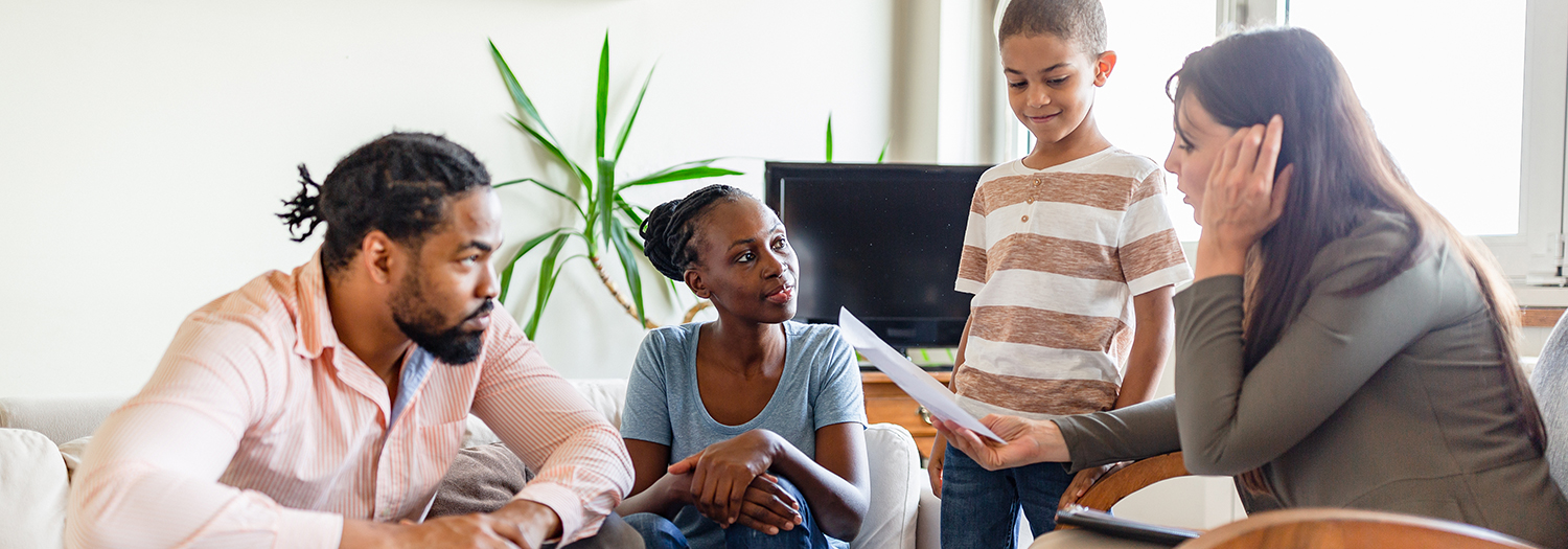Family of three interacting with a social services person in an office